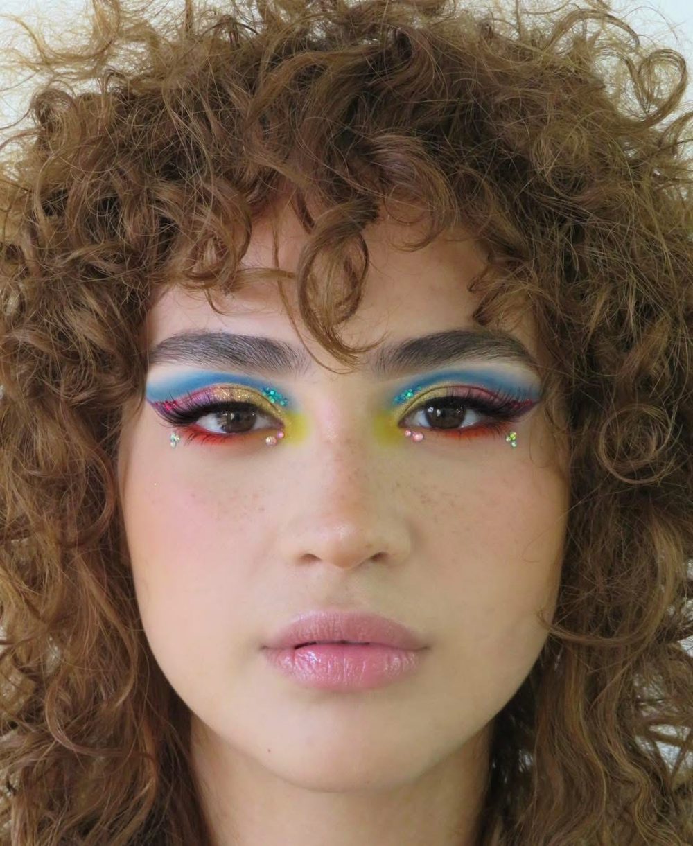 Rainbow graphic eye look with blue, yellow and red shadow and small gems